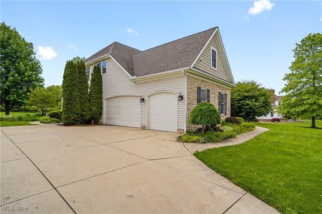 7305 Alexander Rd, Concord, OH 44077 - view of home's exterior with concrete driveway, stone siding, roof with shingles, a lawn, and an attached garage
