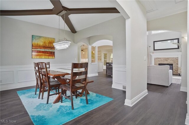 7305 Alexander Rd, Concord, OH 44077 - dining space with a decorative wall, arched walkways, a wainscoted wall, dark wood-style floors, and a stone fireplace