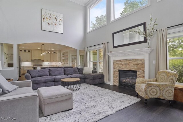 7305 Alexander Rd, Concord, OH 44077 - living area featuring a high ceiling, dark wood-style flooring, a stone fireplace, and arched walkways