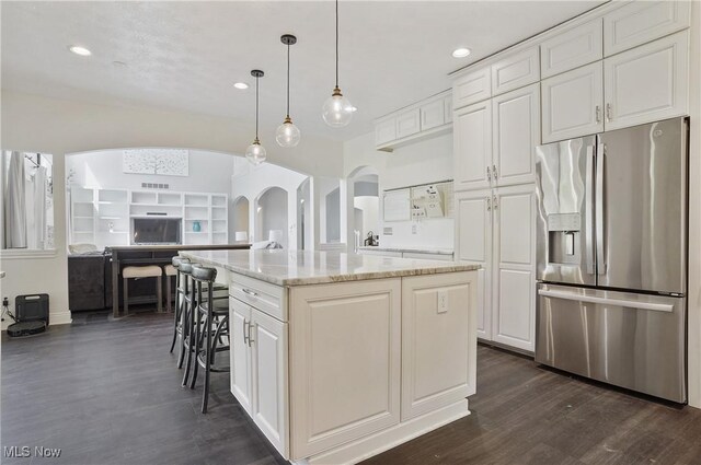 7305 Alexander Rd, Concord, OH 44077 - kitchen featuring stainless steel fridge, arched walkways, dark wood finished floors, a kitchen island, and white cabinets