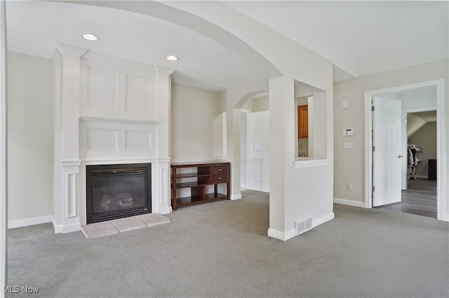 7305 Alexander Rd, Concord, OH 44077 - unfurnished living room featuring carpet flooring, a glass covered fireplace, arched walkways, and recessed lighting