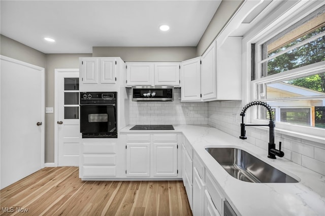 4928 Lane Rd, Perry, OH 44081 - kitchen featuring black appliances, light stone countertops, white cabinetry, decorative backsplash, and light wood finished floors