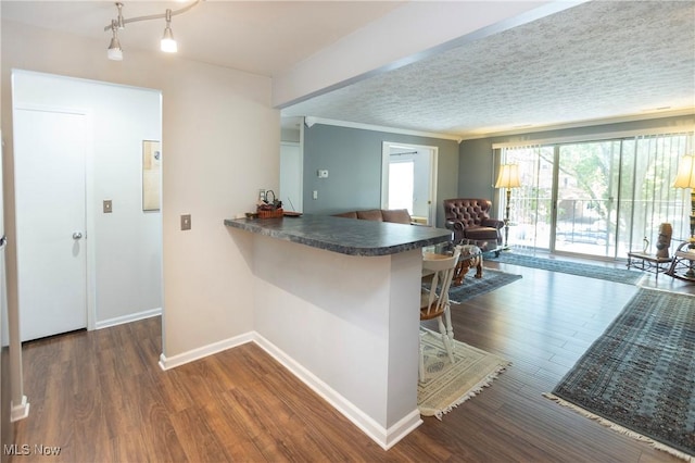 2021 King James Pkwy Unit 214, Westlake, OH 44145 - kitchen with a kitchen breakfast bar, dark countertops, dark wood-type flooring, a peninsula, and crown molding
