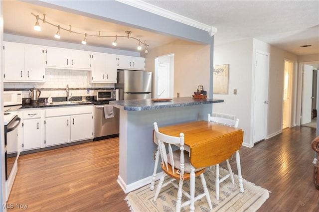 2021 King James Pkwy Unit 214, Westlake, OH 44145 - kitchen featuring appliances with stainless steel finishes, dark countertops, decorative backsplash, wood finished floors, and ornamental molding