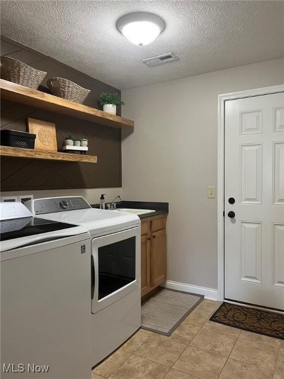 1315 Cascade Cir E, Canton, OH 44708 - laundry area featuring washing machine and dryer, cabinet space, a textured ceiling, and light tile patterned flooring