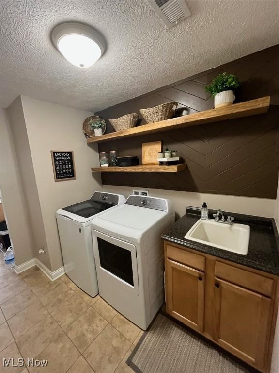 1315 Cascade Cir E, Canton, OH 44708 - laundry area featuring independent washer and dryer, a textured ceiling, light tile patterned floors, and cabinet space