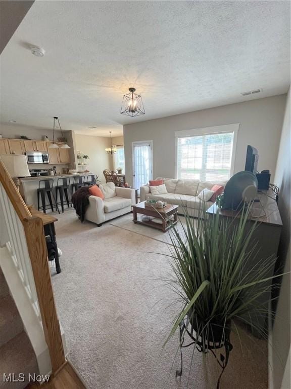 1315 Cascade Cir E, Canton, OH 44708 - living room featuring a chandelier, a textured ceiling, and light colored carpet