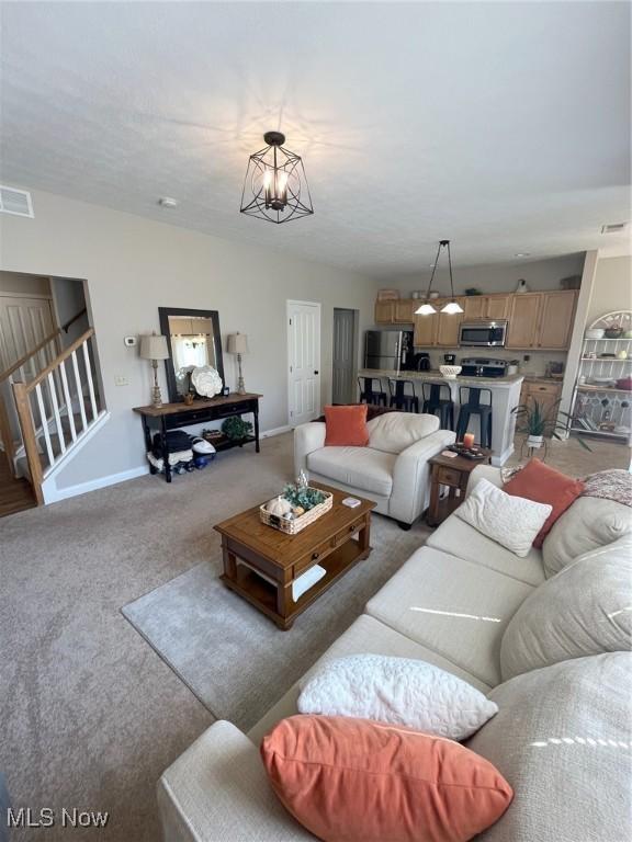 1315 Cascade Cir E, Canton, OH 44708 - living room featuring light colored carpet, stairway, and a chandelier