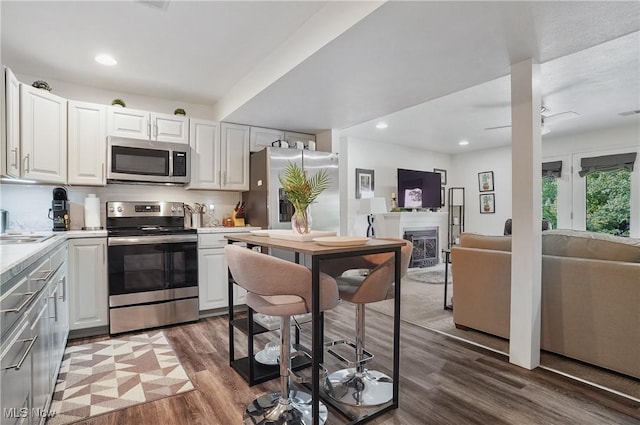 47688 Tomahawk Dr, Negley, OH 44441 - kitchen featuring stainless steel appliances, wood finished floors, light countertops, white cabinets, and open floor plan