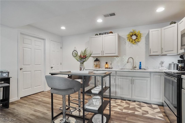 47688 Tomahawk Dr, Negley, OH 44441 - kitchen with appliances with stainless steel finishes, light wood-style floors, backsplash, white cabinetry, and recessed lighting