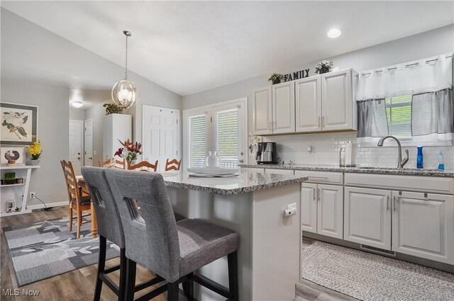 47688 Tomahawk Dr, Negley, OH 44441 - kitchen featuring vaulted ceiling, a breakfast bar area, tasteful backsplash, light stone countertops, and a center island