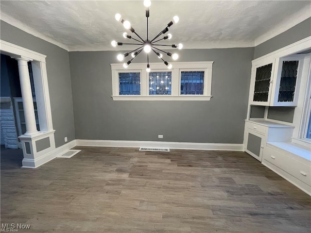 10003 Empire Ave, Cleveland, OH 44108 - unfurnished dining area with a chandelier, dark wood-style floors, and decorative columns