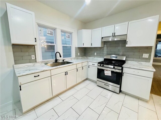 10003 Empire Ave, Cleveland, OH 44108 - kitchen with gas range, under cabinet range hood, light marble finish floors, white cabinetry, and backsplash