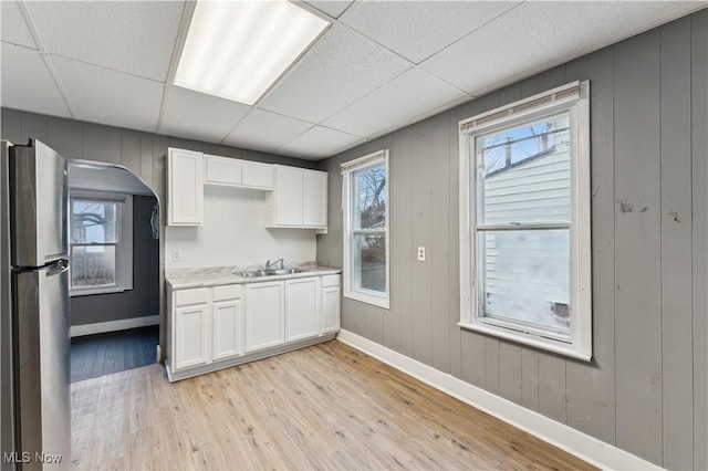4002 Ardmore Ave, Cleveland, OH 44109 - kitchen with freestanding refrigerator, white cabinetry, light wood-type flooring, light countertops, and a drop ceiling