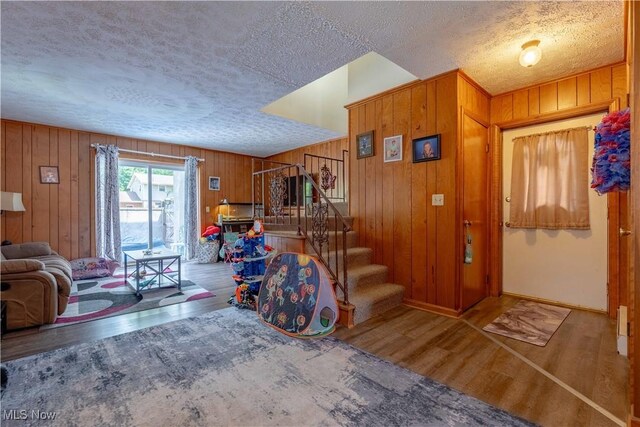 1715 High St, Louisville, OH 44641 - living room with wood finished floors, a textured ceiling, stairs, and wooden walls