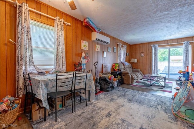 1715 High St, Louisville, OH 44641 - dining space featuring a wall unit AC, a textured ceiling, wood finished floors, wooden walls, and ceiling fan
