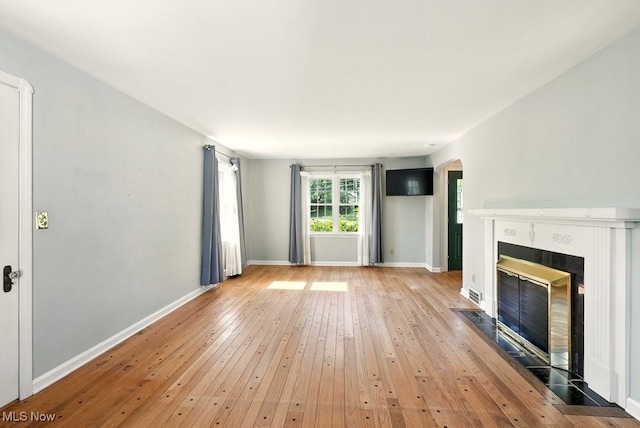 5105 E Sprague Rd, Independence, OH 44131 - unfurnished living room featuring a tiled fireplace, light wood finished floors, and arched walkways