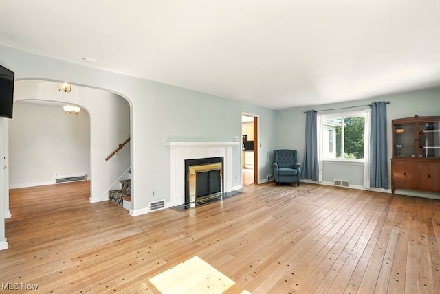5105 E Sprague Rd, Independence, OH 44131 - unfurnished living room featuring wood-type flooring, arched walkways, stairway, and a fireplace with flush hearth