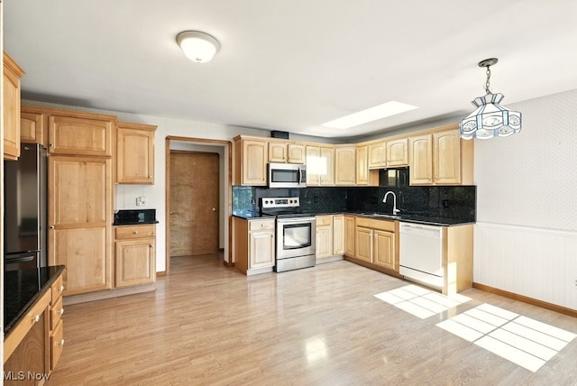 5105 E Sprague Rd, Independence, OH 44131 - kitchen with appliances with stainless steel finishes, light brown cabinets, dark countertops, a wainscoted wall, and wallpapered walls
