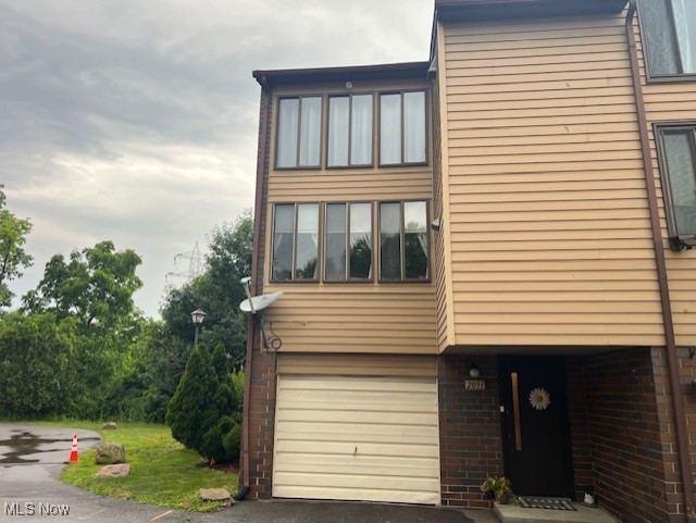 2091 Penguin Ave, Akron, OH 44319 - view of property with an attached garage, brick siding, and asphalt driveway