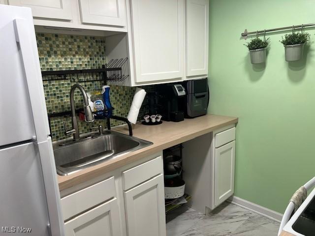 2091 Penguin Ave, Akron, OH 44319 - kitchen with freestanding refrigerator, decorative backsplash, light marble finish floors, white cabinets, and light countertops