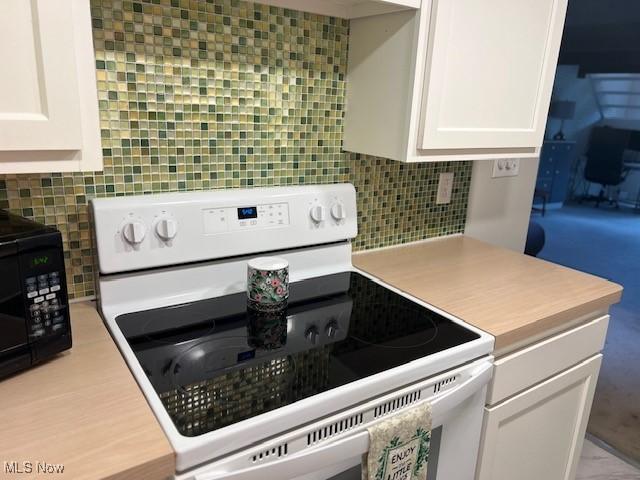 2091 Penguin Ave, Akron, OH 44319 - kitchen with electric range, black microwave, white cabinetry, light countertops, and backsplash