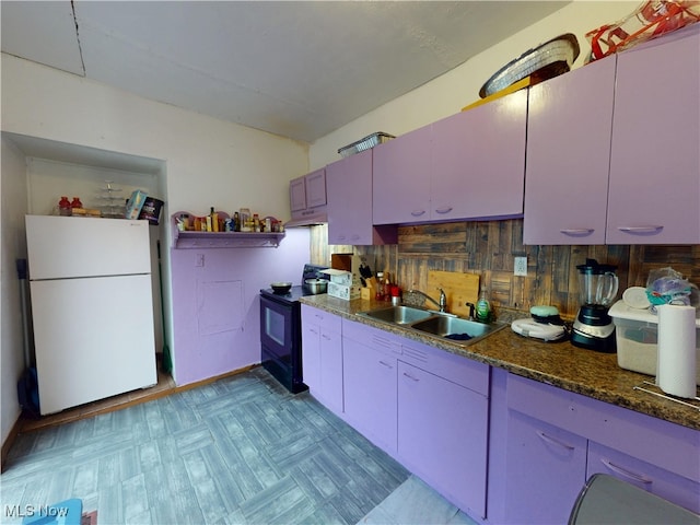 2027 Lexington Ave, Lorain, OH 44052 - kitchen featuring freestanding refrigerator, black electric range oven, dark stone counters, under cabinet range hood, and decorative backsplash