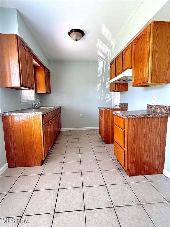 kitchen featuring brown cabinets, light tile patterned floors, and under cabinet range hood