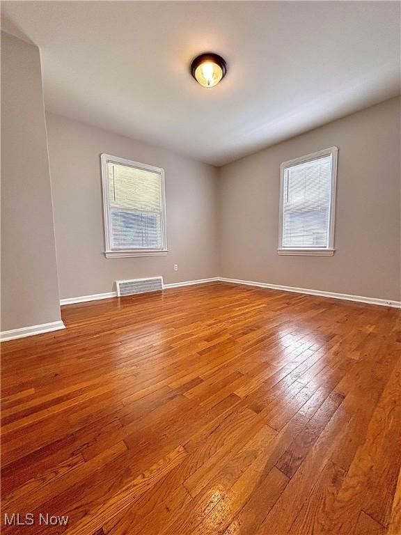 spare room featuring hardwood / wood-style flooring and baseboards
