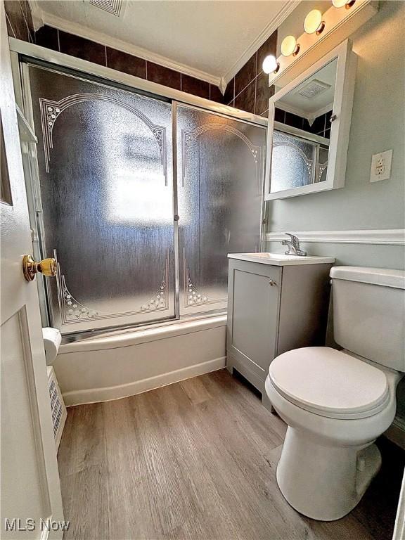 full bathroom with wood finished floors, enclosed tub / shower combo, vanity, and crown molding