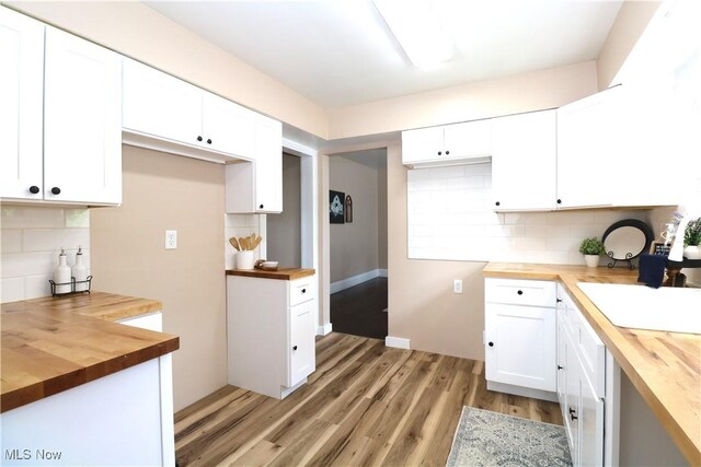 1120 Delia Ave, Akron, OH 44320 - kitchen with butcher block countertops, tasteful backsplash, light wood finished floors, and white cabinetry