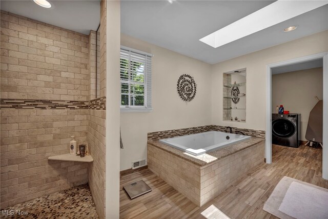 561 Willard Rd, Aurora, OH 44202 - bathroom with washer / clothes dryer, a skylight, wood finished floors, a bath, and a tile shower