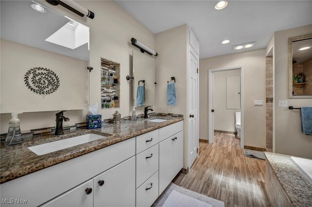 561 Willard Rd, Aurora, OH 44202 - bathroom featuring double vanity, wood finished floors, recessed lighting, a tile shower, and a skylight