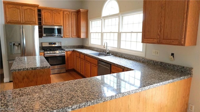 1519 Mctaggart Rd, Stow, OH 44224 - kitchen featuring appliances with stainless steel finishes, light wood-style flooring, brown cabinetry, dark stone countertops, and a center island