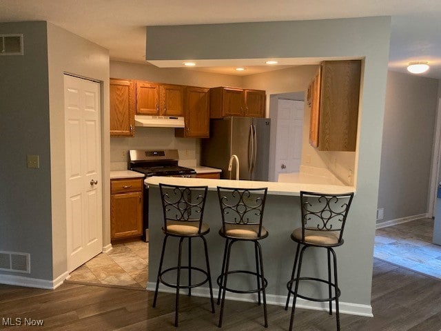 205 S Aspen Unit 4, Warren, OH 44484 - kitchen featuring stainless steel appliances, under cabinet range hood, a breakfast bar area, a peninsula, and wood finished floors
