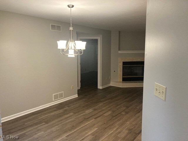 205 S Aspen Unit 4, Warren, OH 44484 - unfurnished dining area with dark wood-type flooring, a chandelier, and a glass covered fireplace