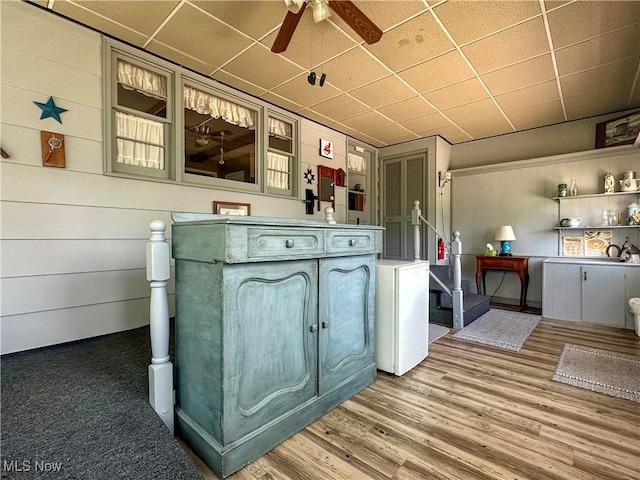 30 Bond St, Niles, OH 44446 - kitchen featuring ceiling fan, a drop ceiling, wood finished floors, wood walls, and glass insert cabinets