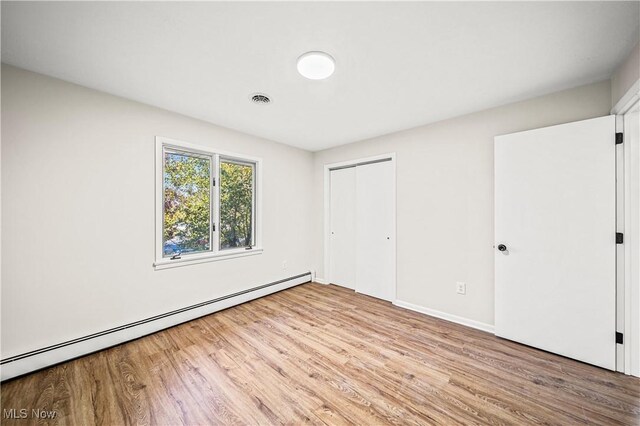 30529 Ridge Rd, Wickliffe, OH 44092 - unfurnished bedroom with a baseboard heating unit, wood finished floors, and a closet