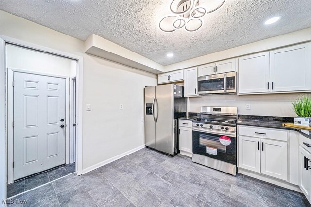 30529 Ridge Rd, Wickliffe, OH 44092 - kitchen with stainless steel appliances, dark countertops, white cabinetry, a textured ceiling, and recessed lighting