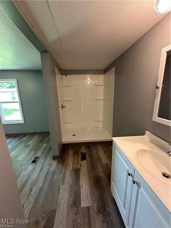7443 Spillway Rd Unit 63, Lisbon, OH 44432 - bathroom featuring vanity, a textured ceiling, wood finished floors, and a shower