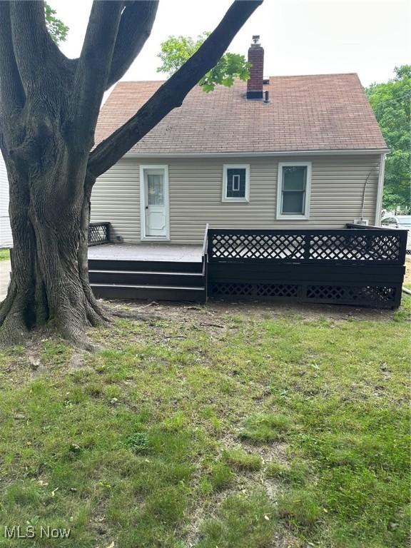 1042 Frederick Blvd, Akron, OH 44320 - back of property featuring a chimney, a deck, a lawn, and roof with shingles