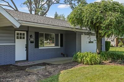 6265 Thunderbird Dr, Mentor, OH 44060 - entrance to property with brick siding, a porch, and a lawn