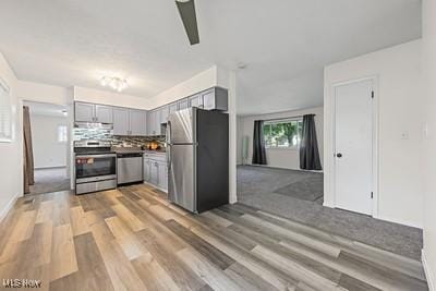 6265 Thunderbird Dr, Mentor, OH 44060 - kitchen featuring stainless steel appliances, gray cabinets, light wood-style floors, range hood, and backsplash