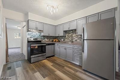6265 Thunderbird Dr, Mentor, OH 44060 - kitchen with stainless steel appliances, gray cabinets, under cabinet range hood, and dark wood-type flooring