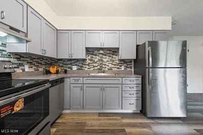 6265 Thunderbird Dr, Mentor, OH 44060 - kitchen with stainless steel appliances, wood finished floors, decorative backsplash, under cabinet range hood, and light countertops