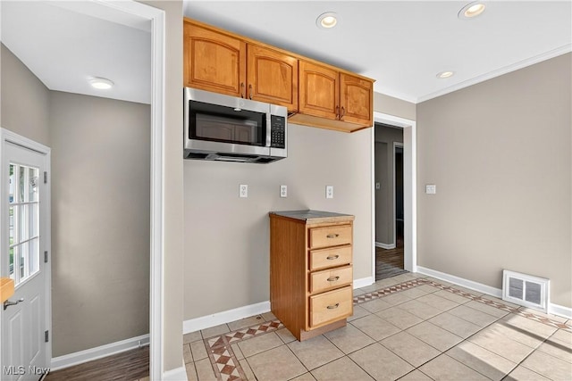 841 E 216th St, Euclid, OH 44119 - kitchen with stainless steel microwave, light tile patterned floors, brown cabinetry, and recessed lighting