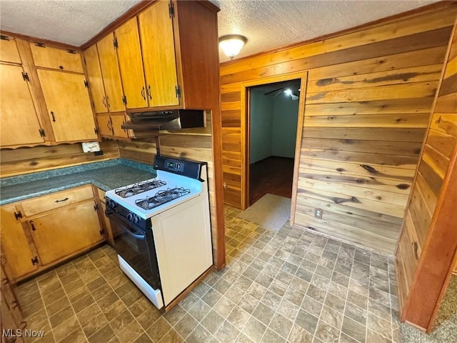 33 Knight Ln, Big Bend, WV 26136 - kitchen with gas range, a textured ceiling, under cabinet range hood, wood walls, and brown cabinets