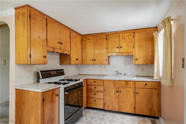 1713 26th St, Parkersburg, WV 26101 - kitchen featuring gas stove, light floors, light countertops, arched walkways, and brown cabinetry