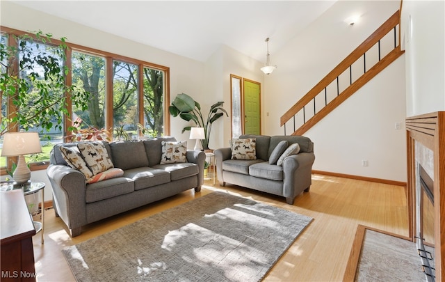 82 Pyle Rd, Oberlin, OH 44074 - living area featuring stairway, wood finished floors, a fireplace with flush hearth, and vaulted ceiling