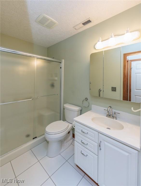373 Chesapeake Cv, Painesville, OH 44077 - full bathroom featuring vanity, a textured ceiling, a shower stall, and tile patterned floors